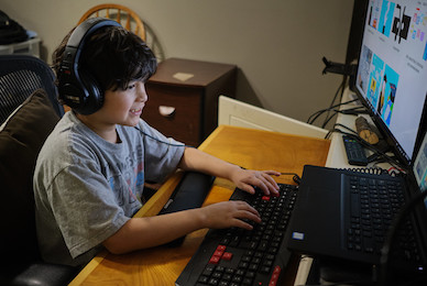  Un niño aprende usando la computadora con unos auriculares puestos.